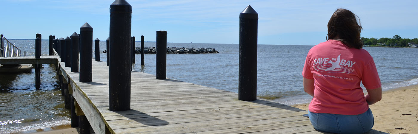 A person sits on a dock wearing a CBF t-shirt.